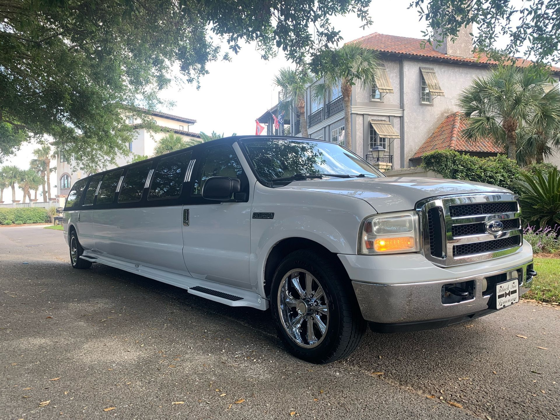 White limousine parked on a paved road, in front of a building.