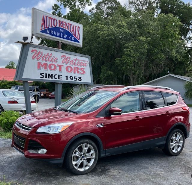 Red Ford Escape SUV parked in front of a car rental business. Sign reads