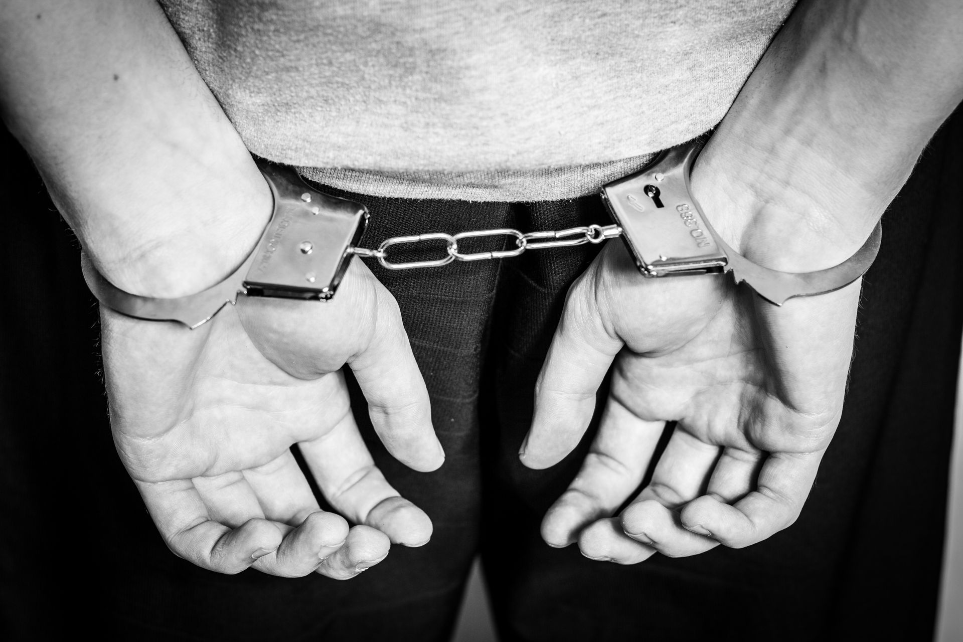 A man is wearing handcuffs with the number 1 on them.