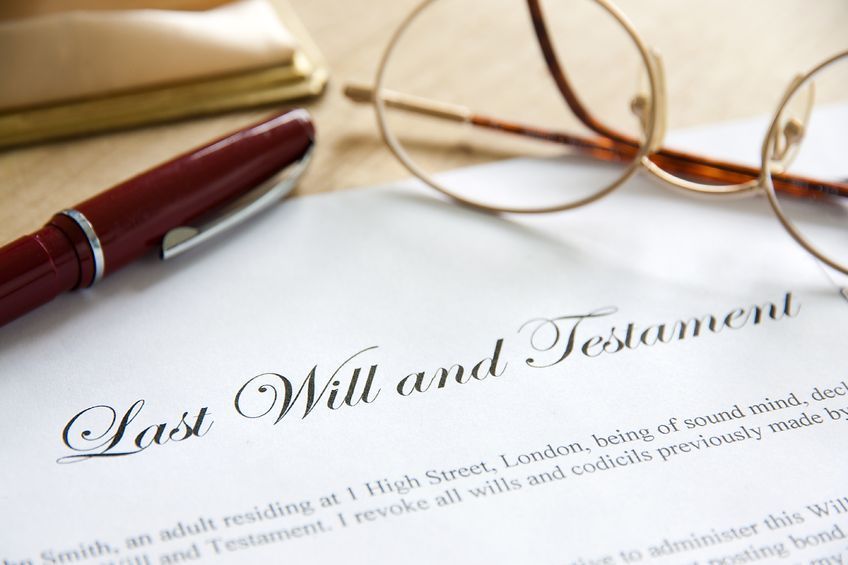 A pen and glasses are on top of a last will and testament