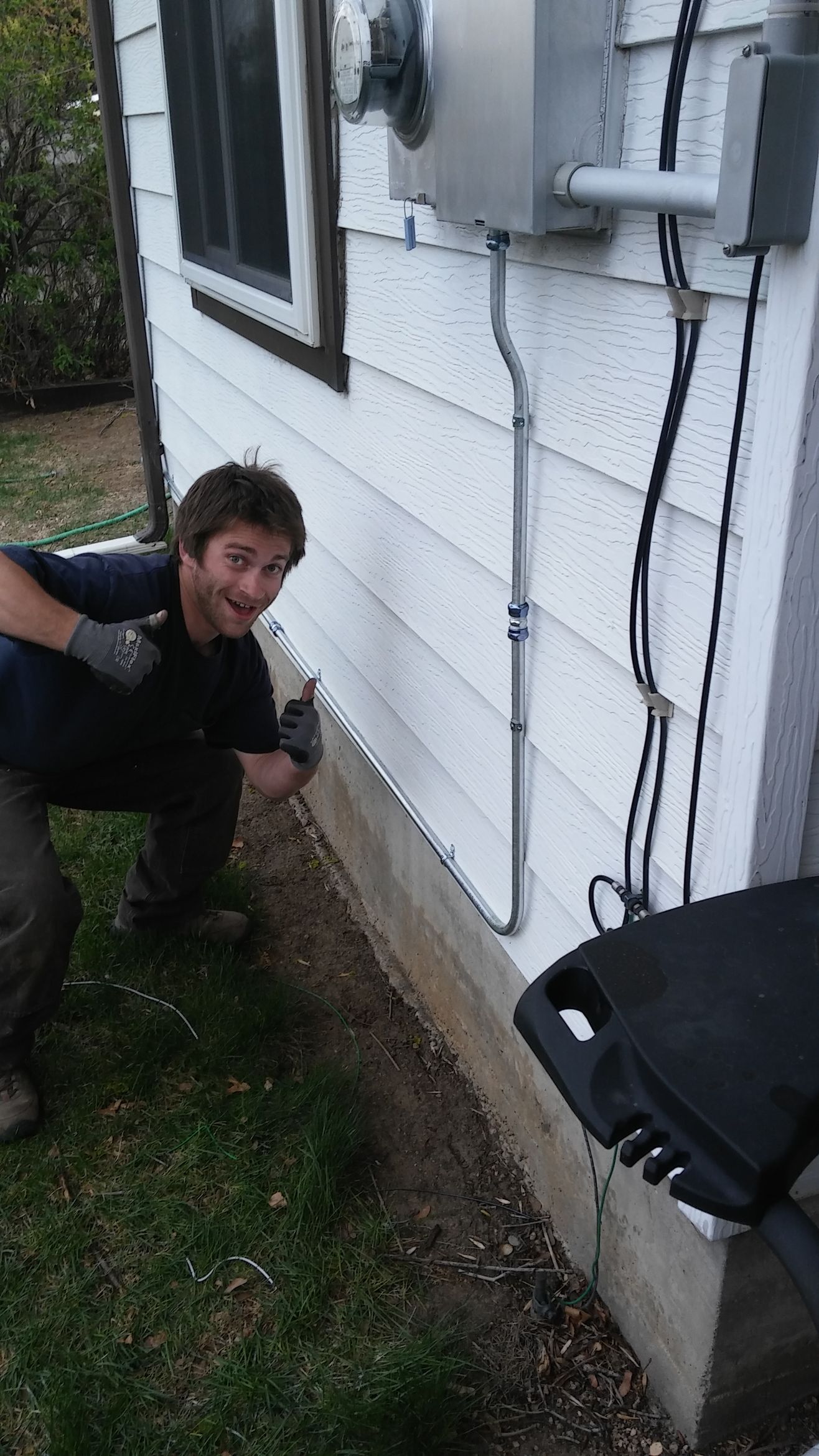 A man is kneeling down in front of a white house.