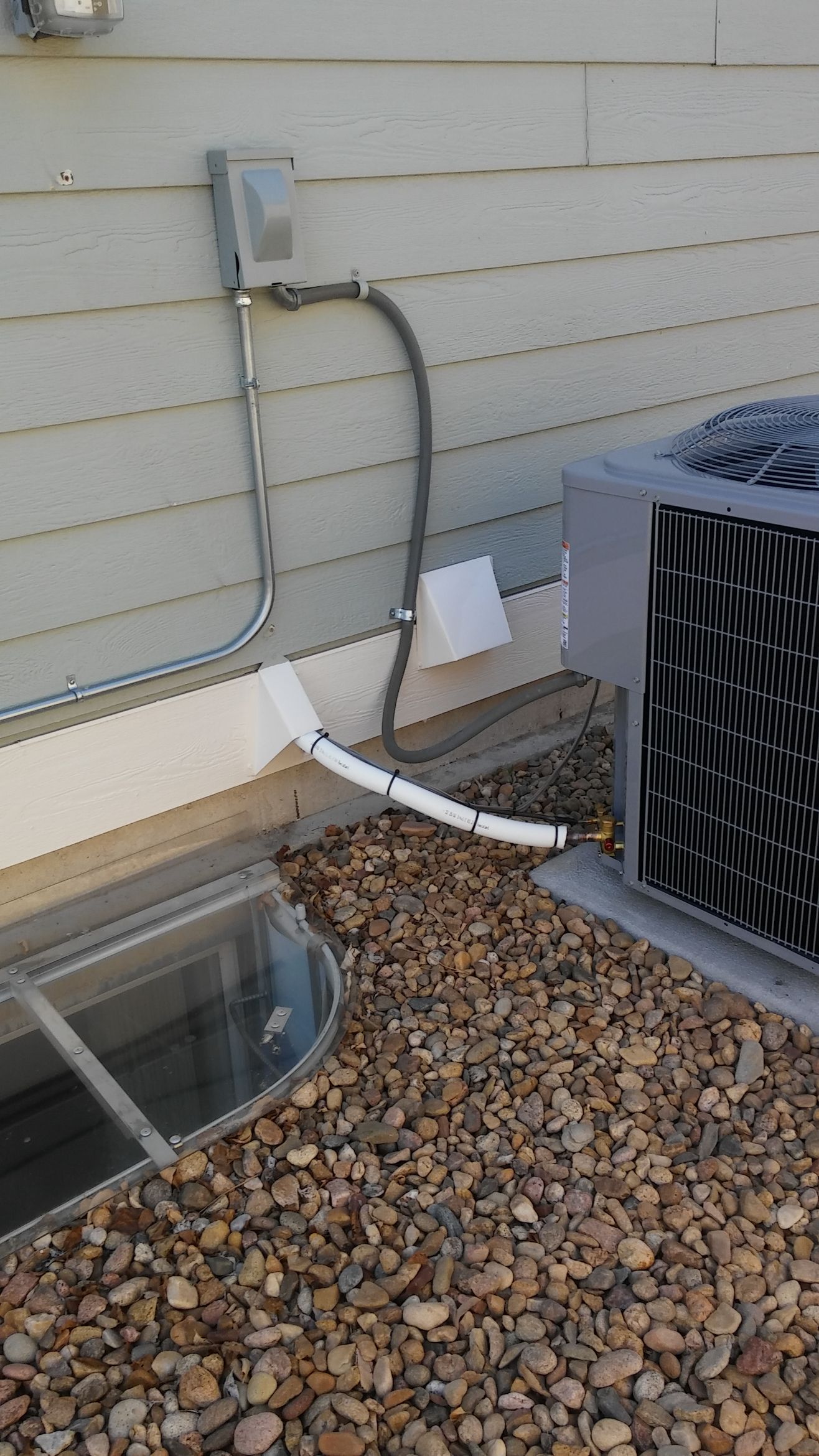 An air conditioner is sitting on the ground next to a house.