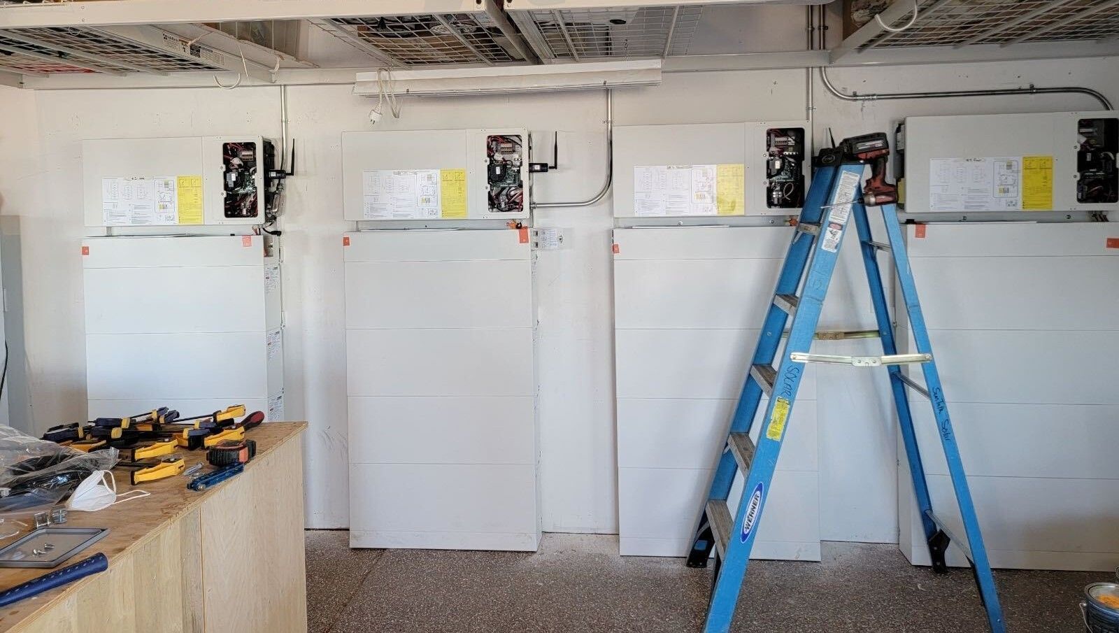 A blue ladder is sitting in a room with white walls.