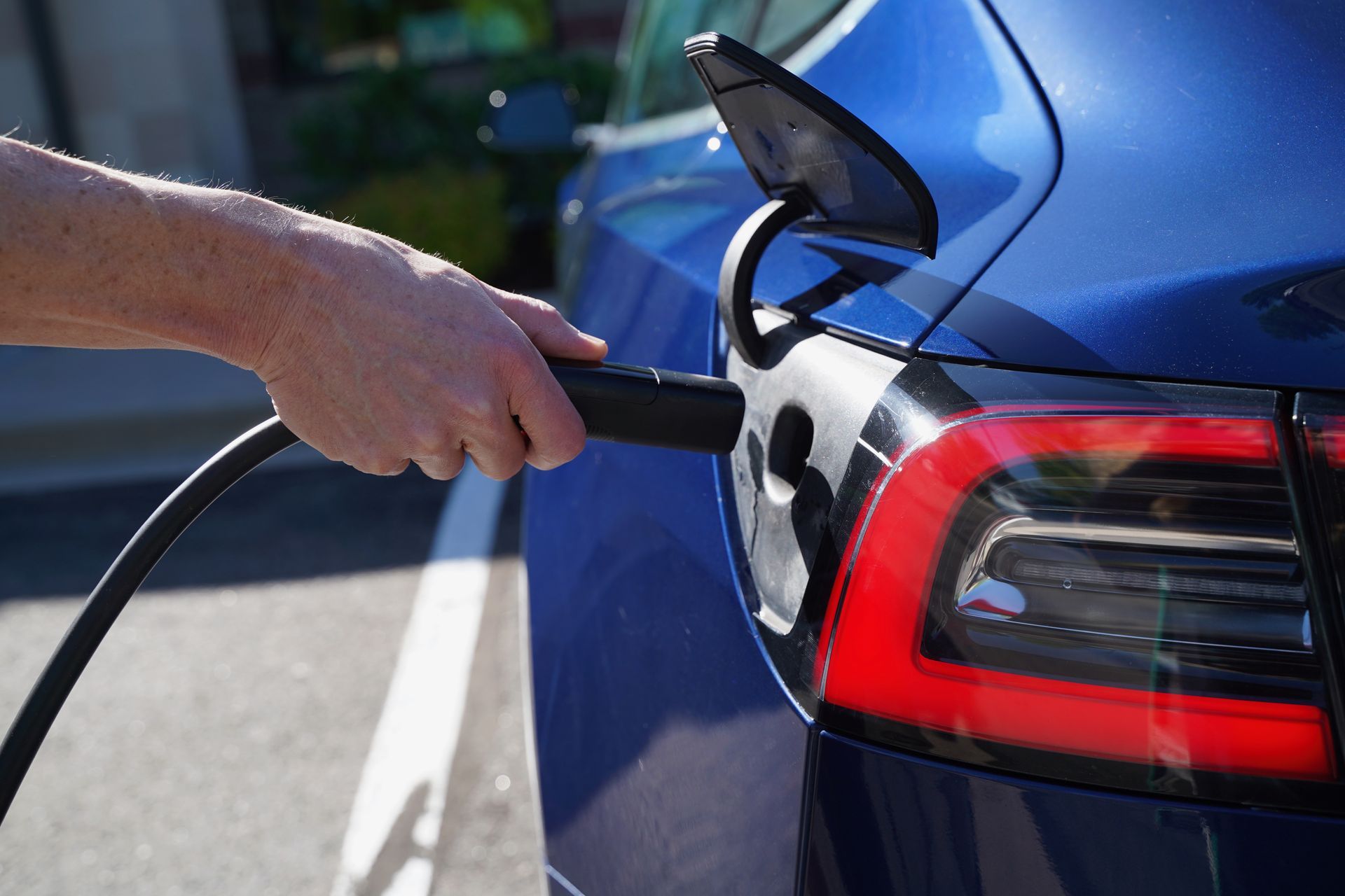 A person is charging an electric car in a parking lot.