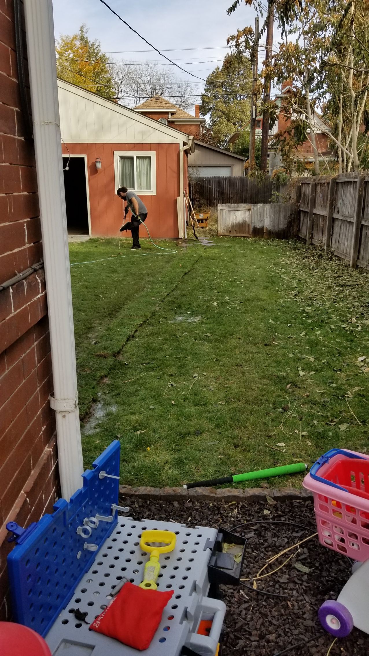 A child is playing in a backyard with a table and toys.