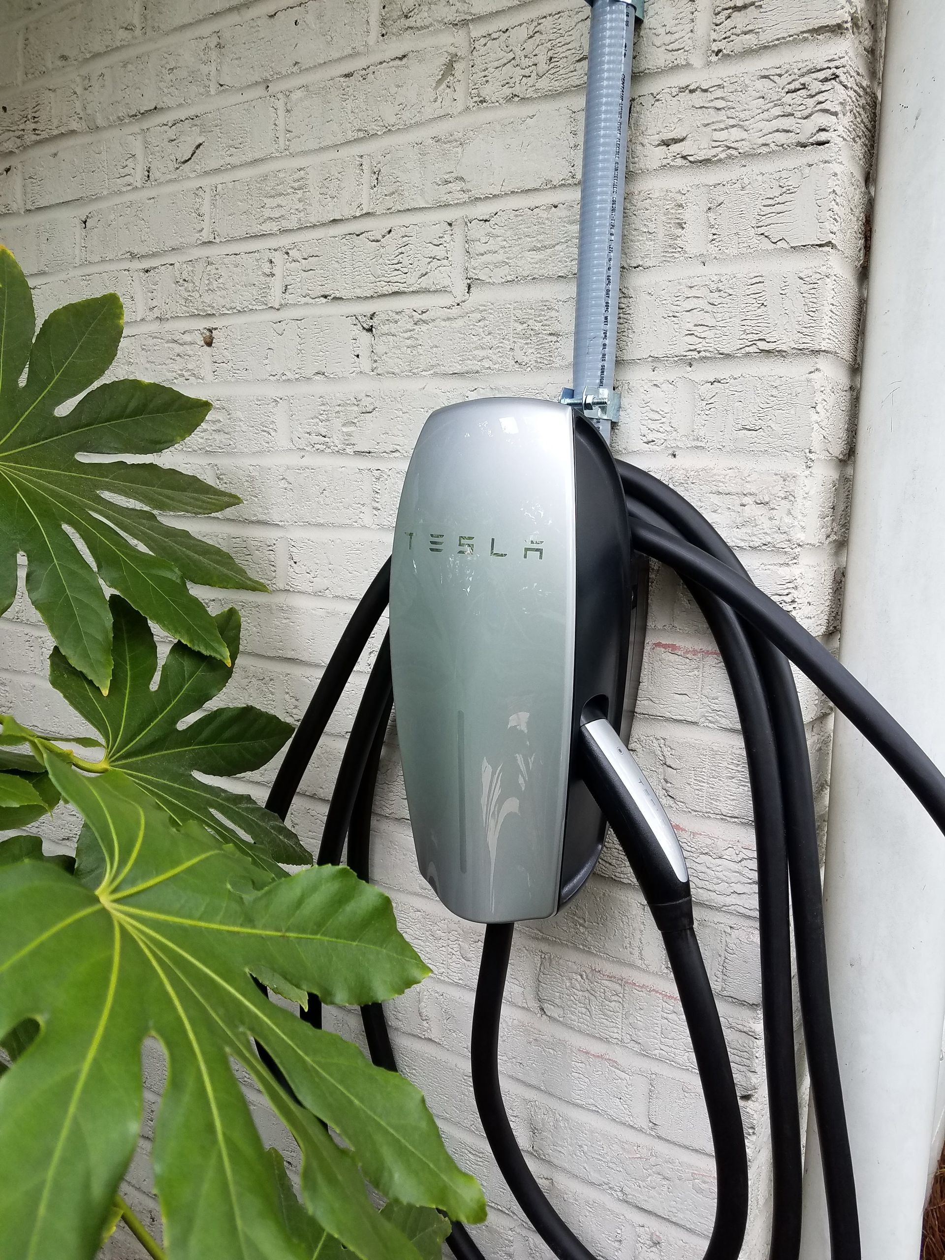 A tesla charging station is attached to a brick wall