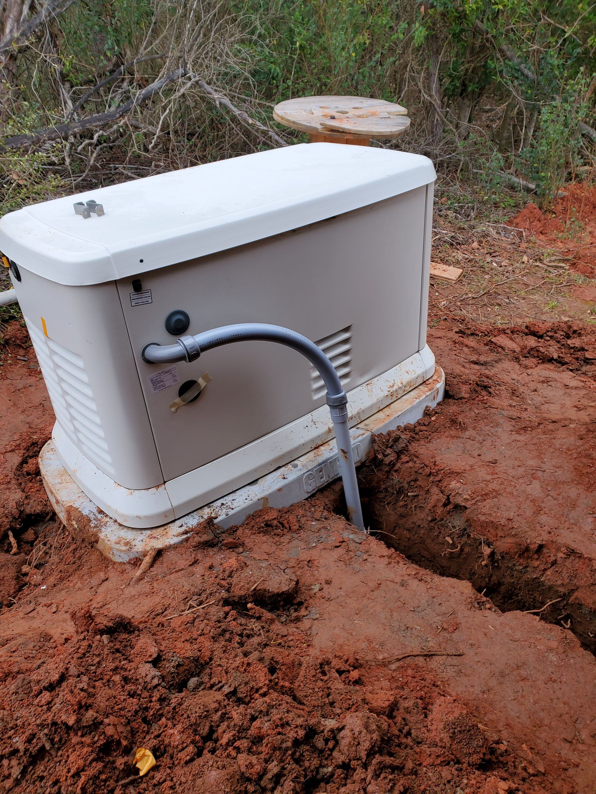 A generator is sitting in the dirt with a hose attached to it.