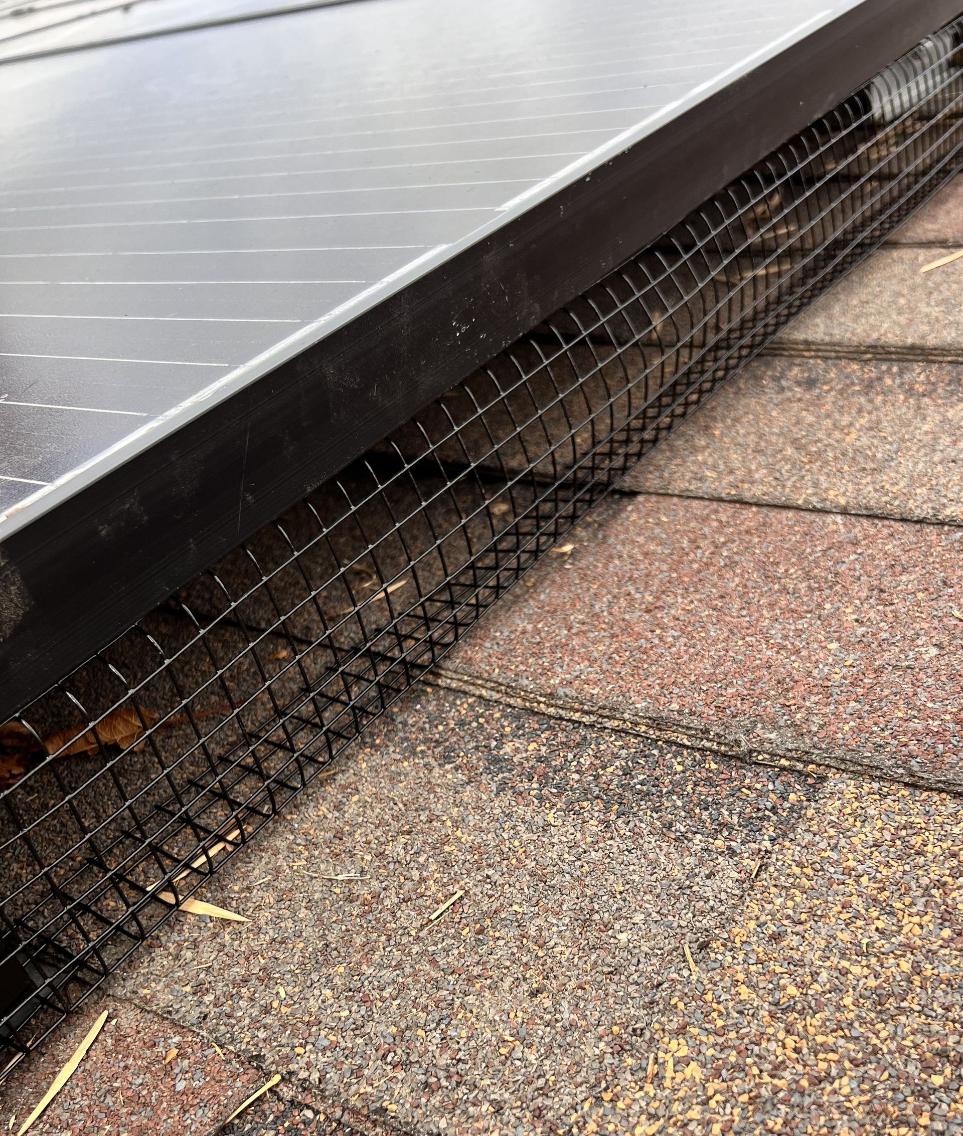 A close up of a roof with a solar panel and a bird fence.