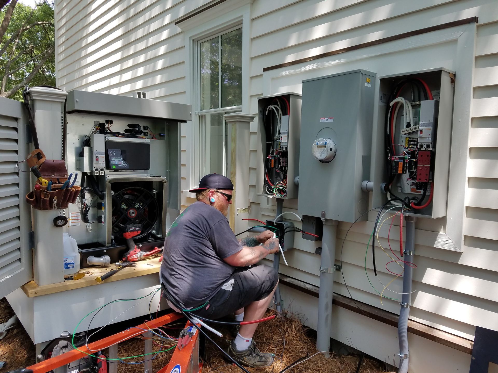 A man is working on an electrical box on the side of a house.