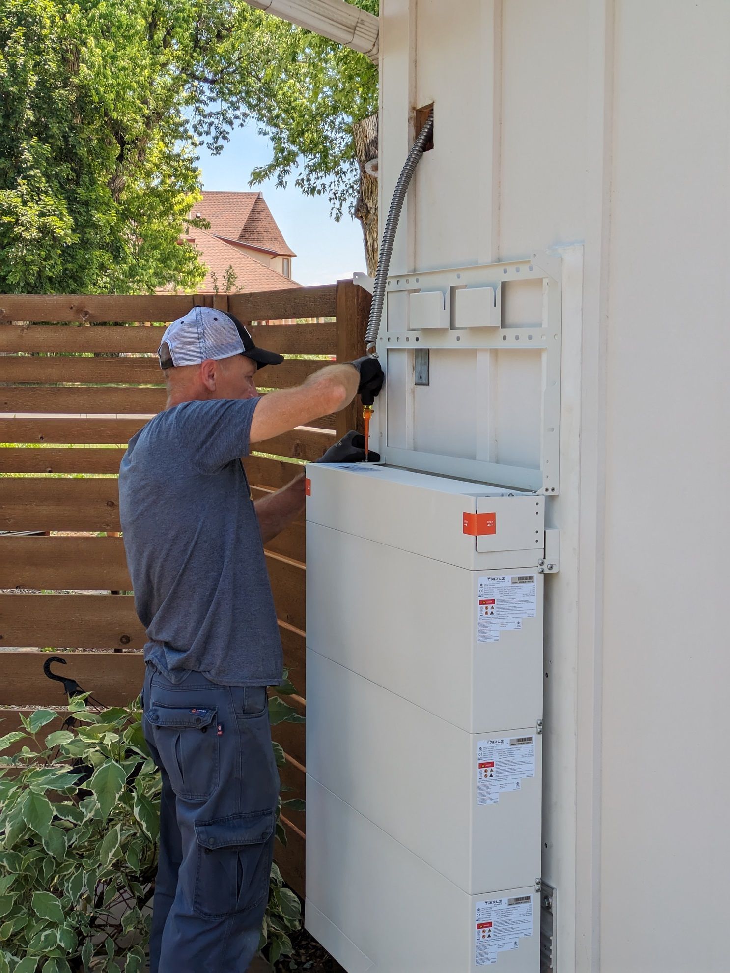 A man is installing a solar panel on the side of a building.
