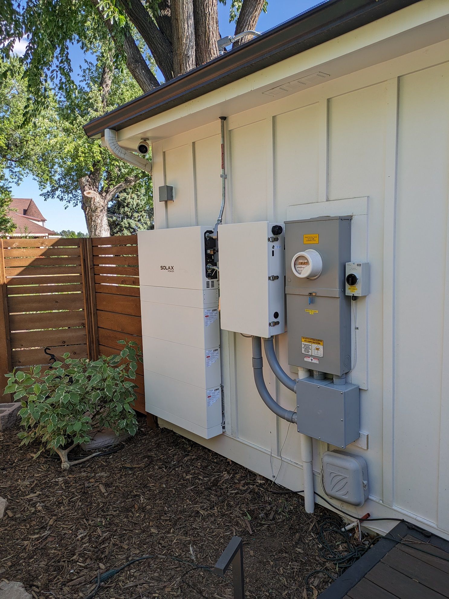 A white house with a lot of electrical equipment on the side of it.