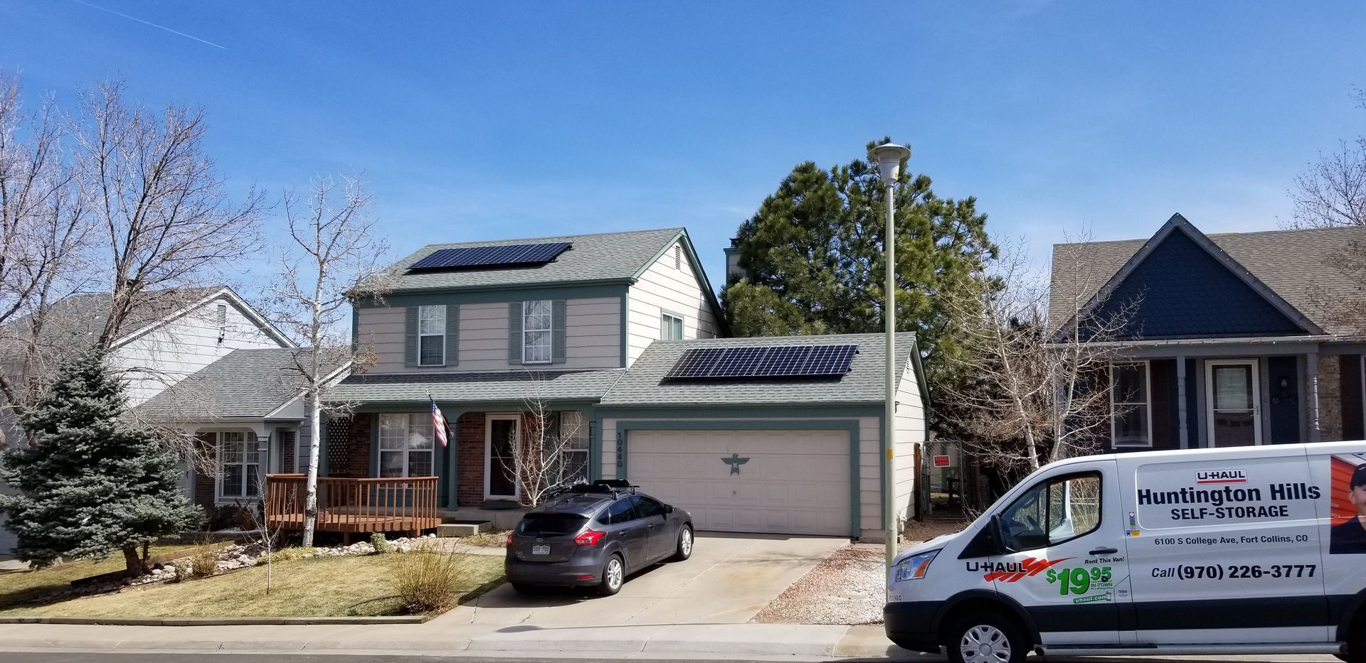 A van is parked in front of a house with solar panels on the roof.