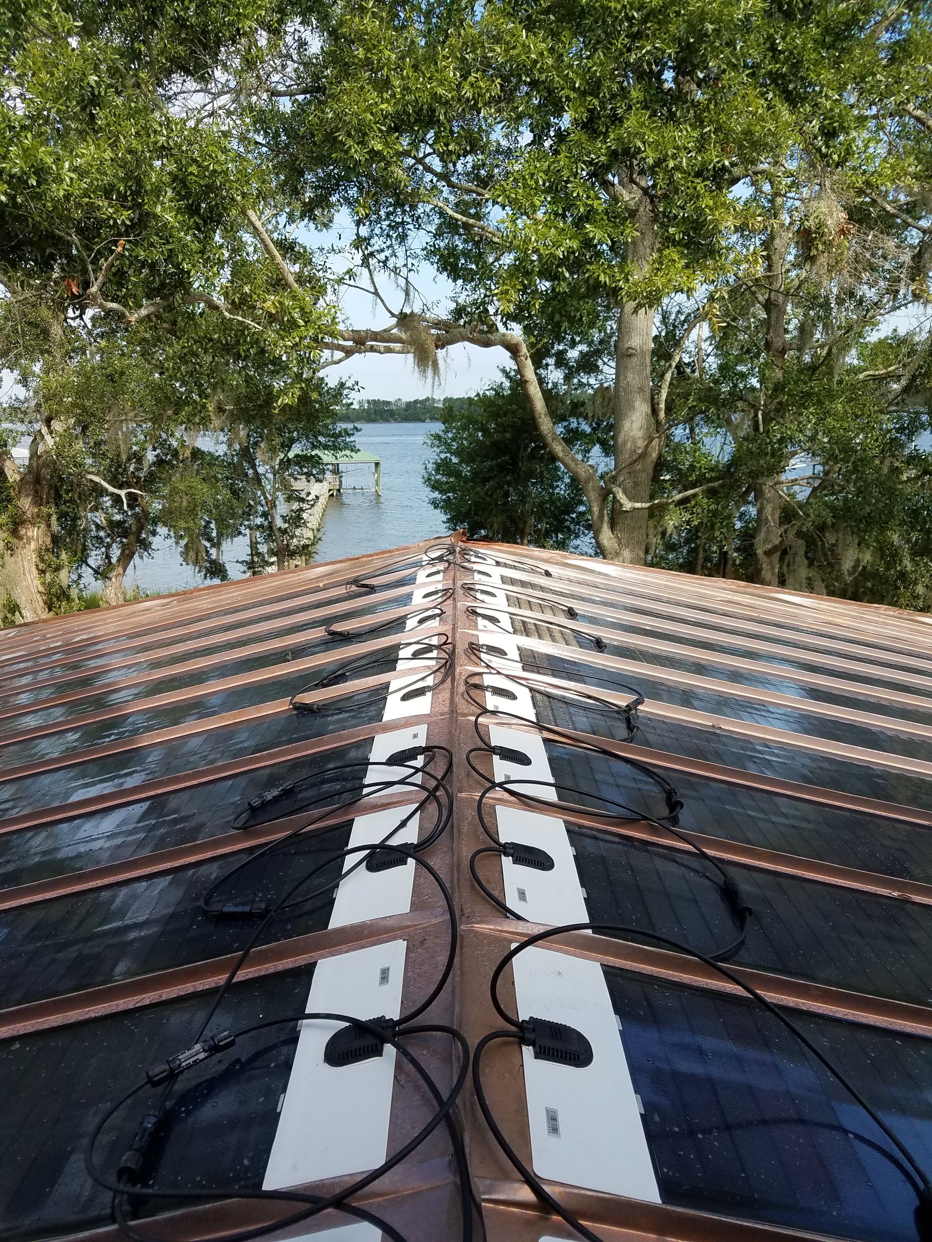 A roof with a lot of solar panels on it and trees in the background.