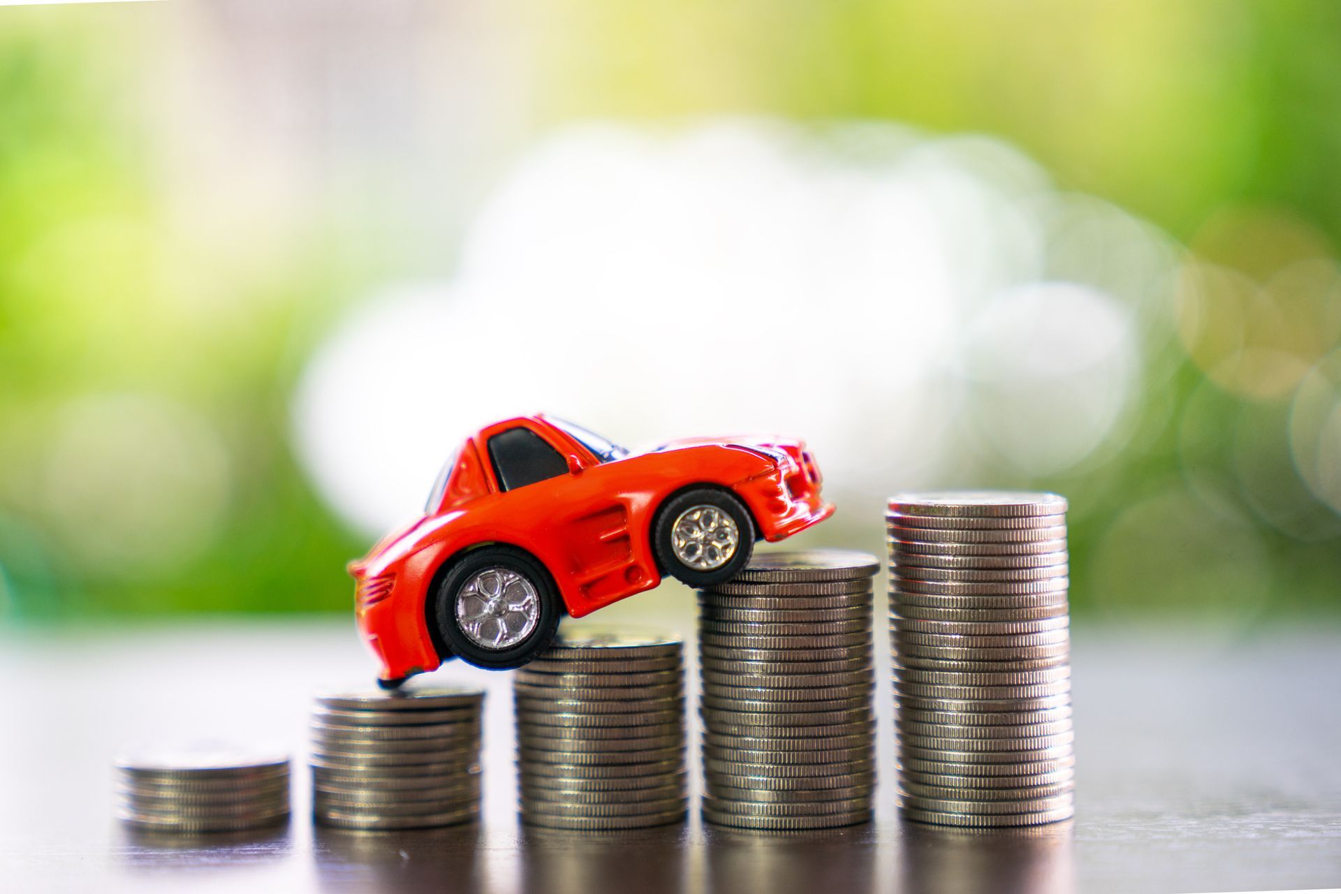 A toy car is sitting on top of a pile of coins.