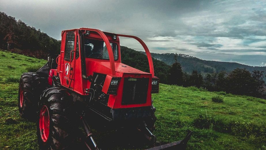 A red tractor is parked in a grassy field.