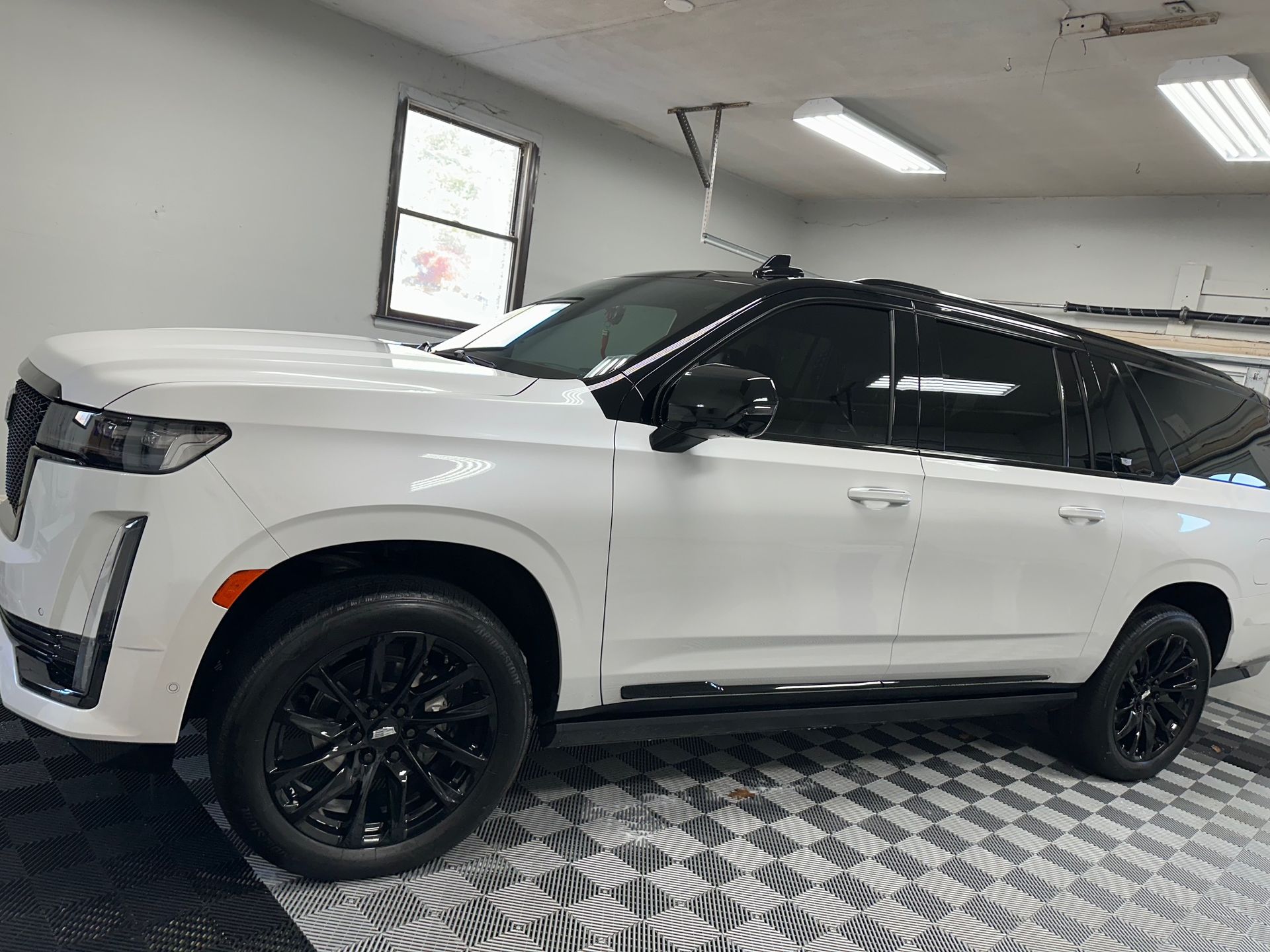 White Cadillac Escalade SUV with black accents in a garage.