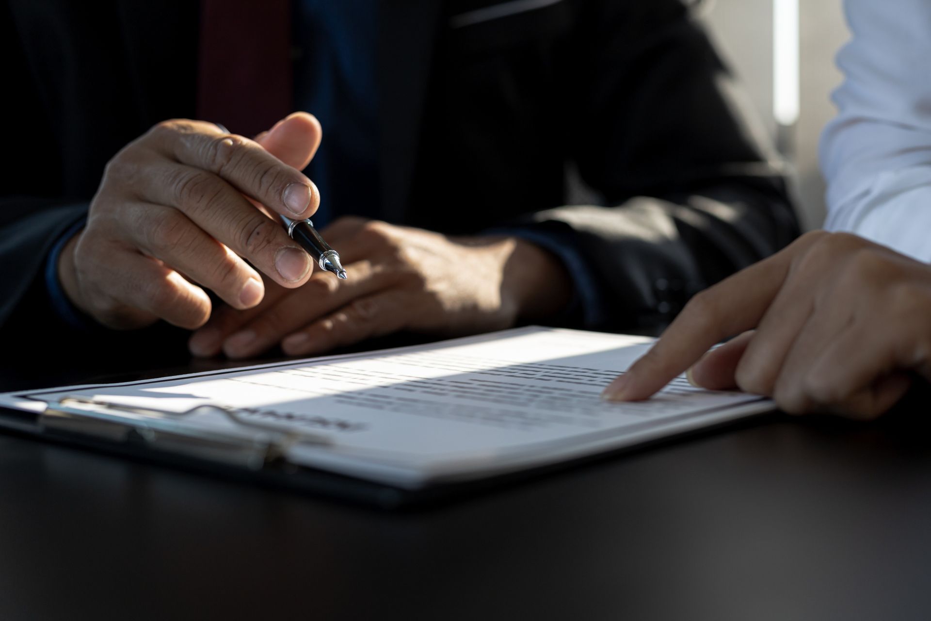 Two people discuss a document, pointing at a form on a table