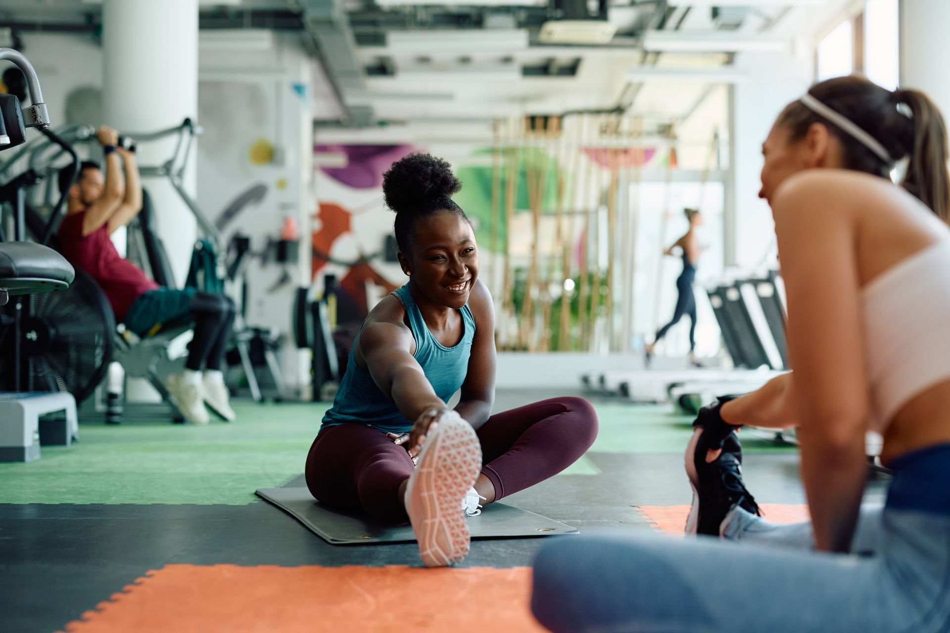Fitness instructor guiding a woman with yellow dumbbells in a bright exercise class