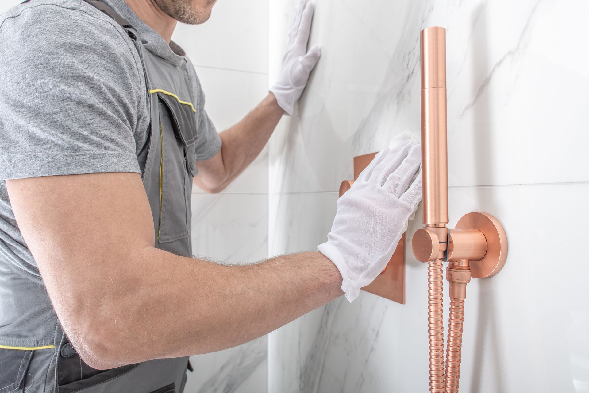 Person installing a copper shower fixture on a tiled bathroom wall