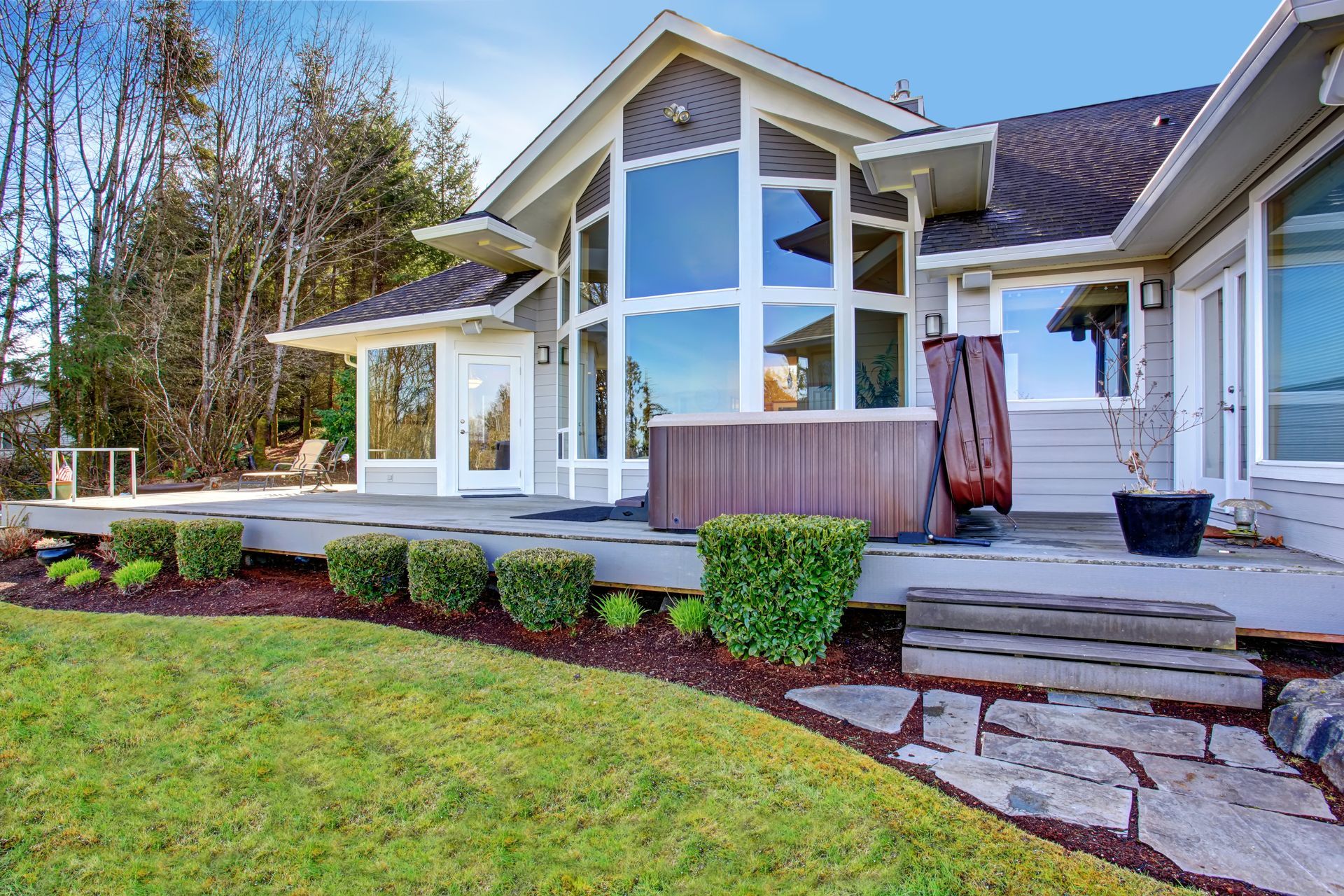Modern house exterior with large windows, stone steps, and a well-kept lawn Modern house exterior with large windows, stone steps, and a well-kept lawn