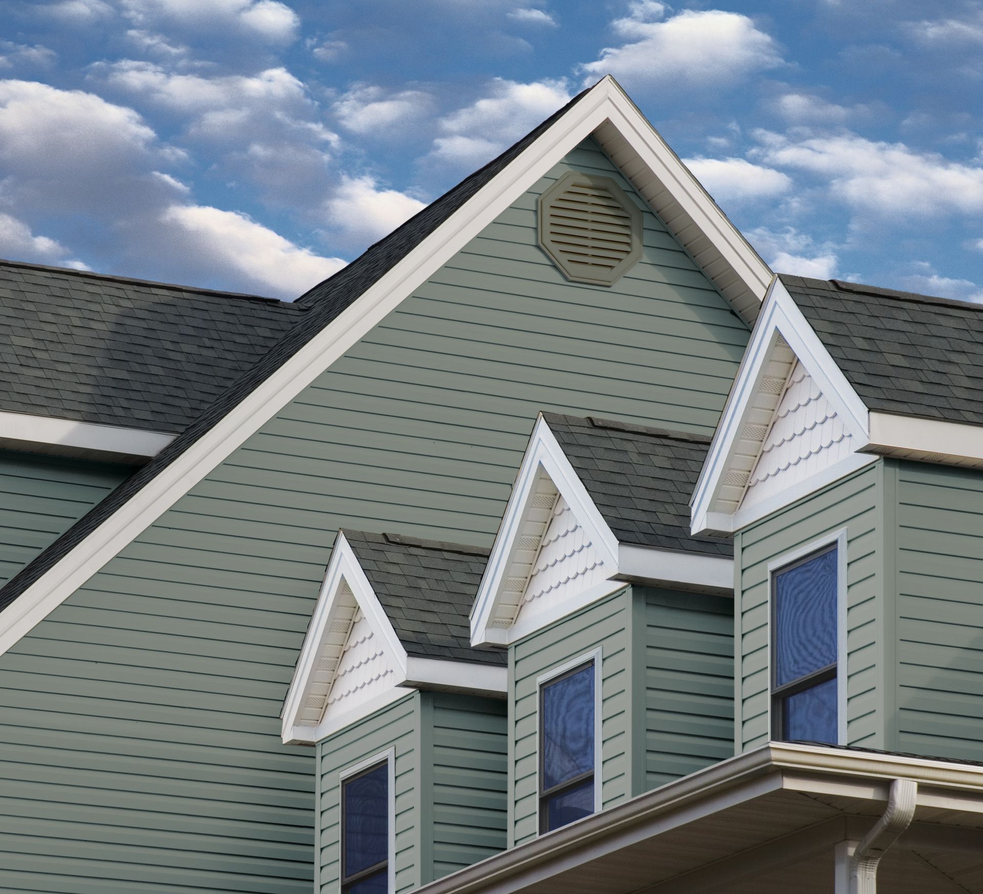 Green house gables with white trim against a blue sky with clouds Green house gables with white trim against a blue sky with clouds