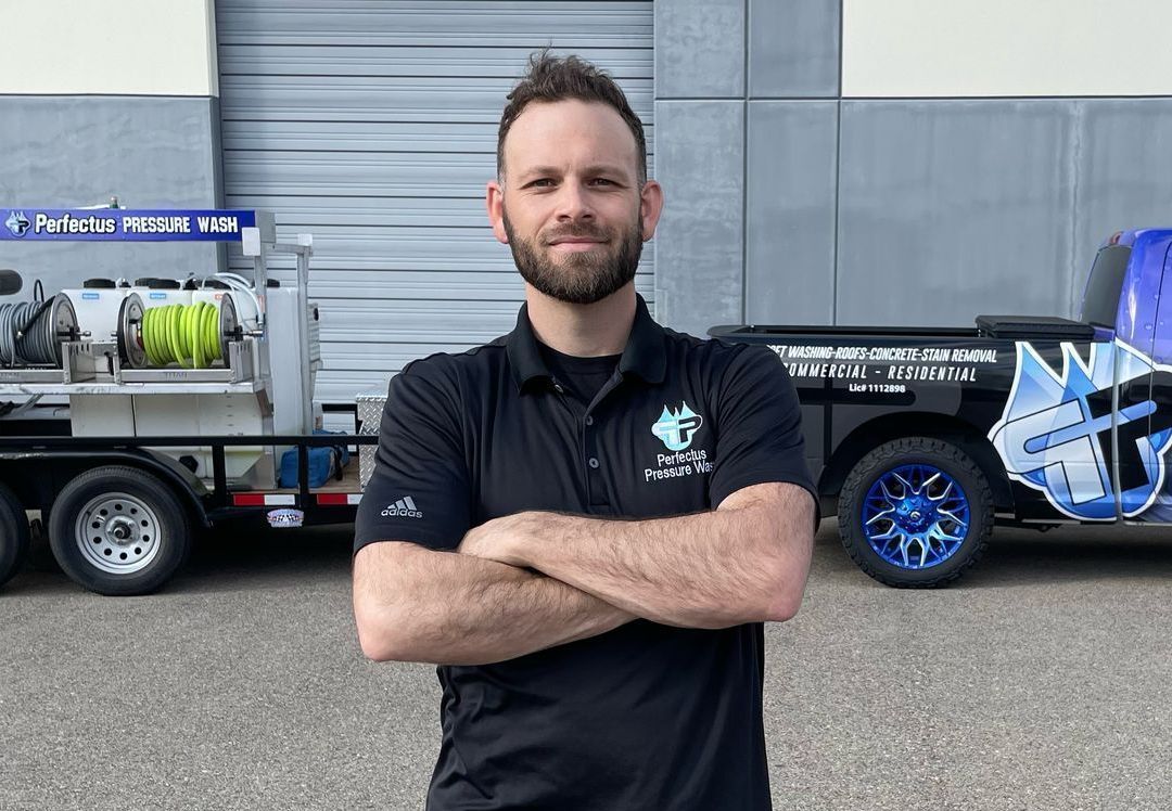 A man is cleaning the side of a building with a hose.