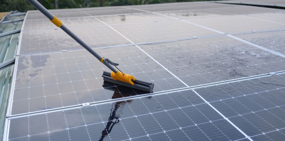 A person is cleaning a solar panel with a broom.