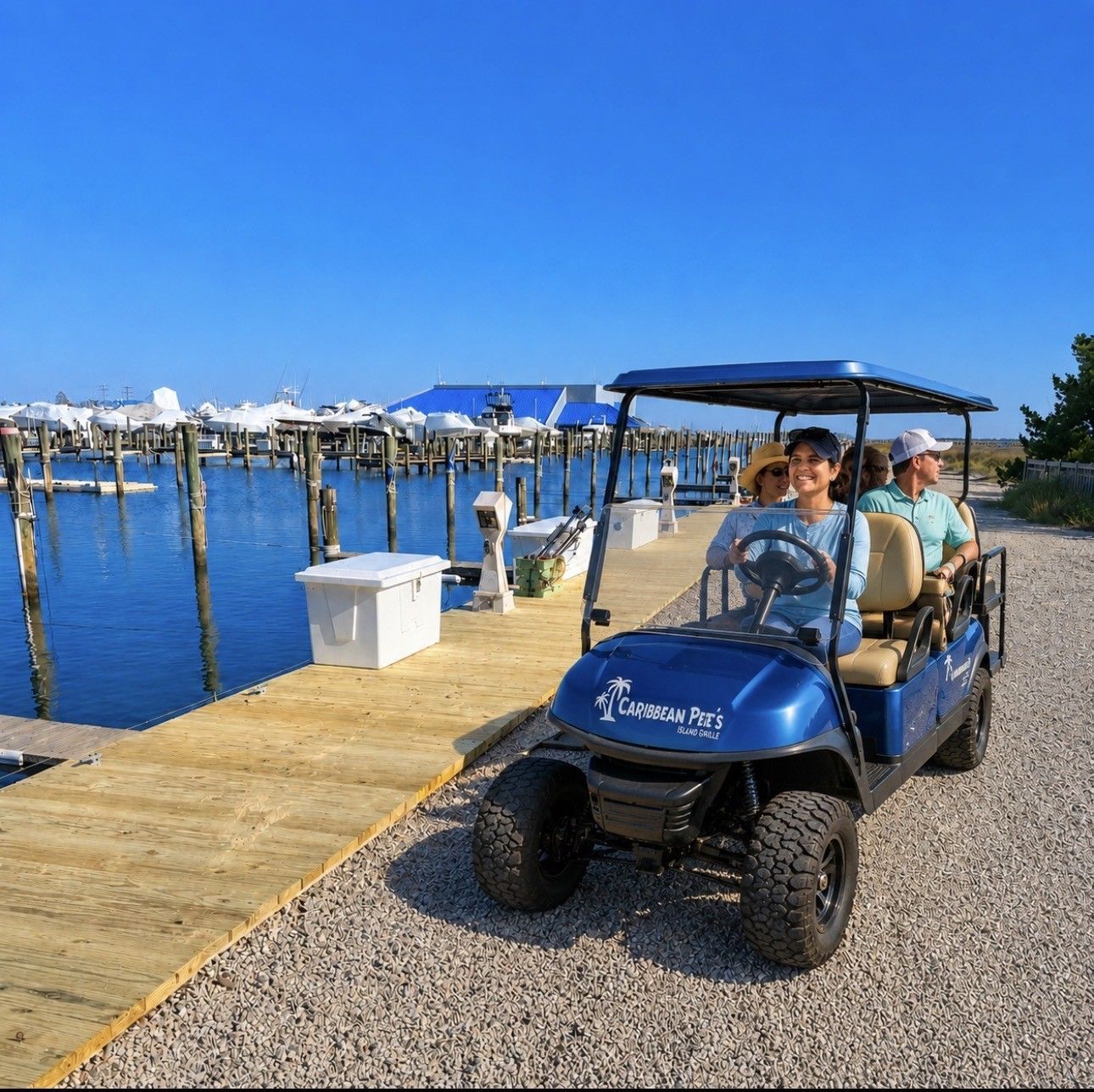 Blue golf cart with passengers on a dock beside calm water under a clear sky