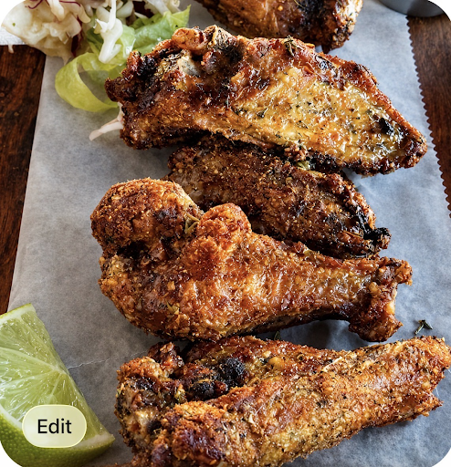 Plate of crispy fried chicken wings on parchment with lime wedges