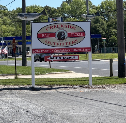 Creekside Bait Tackle Outfitters roadside sign on a sunny street, white and red lettering on a white frame