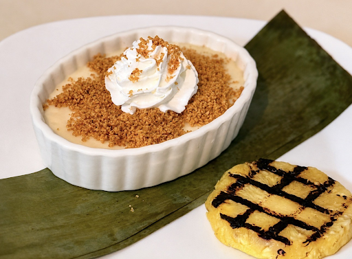 Dessert on a banana leaf: white custard with crumb topping and whipped cream, plus a grilled yellow pastry.