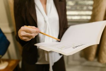 A woman is holding a pencil and a piece of paper.