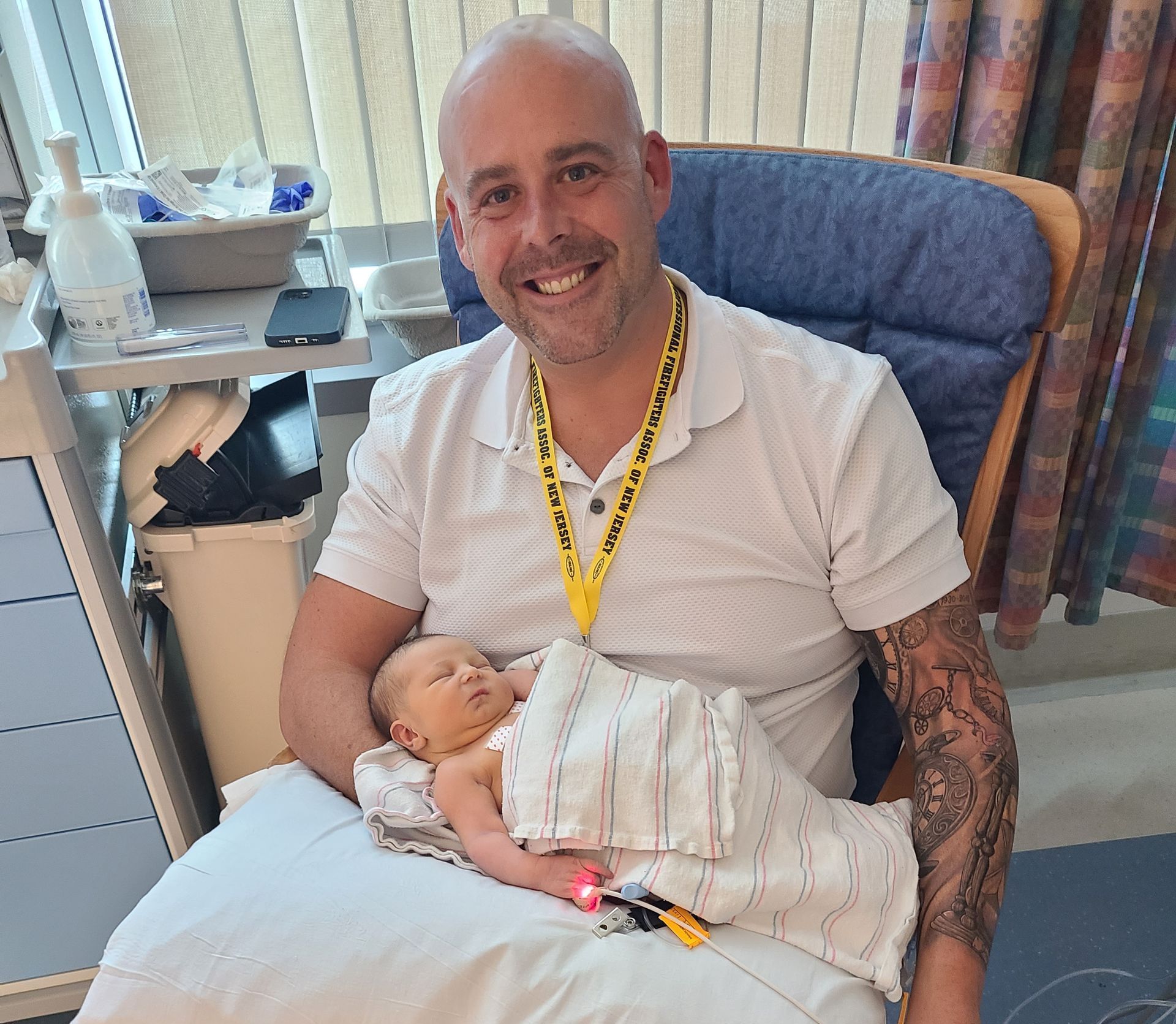 A man is holding a baby in his lap in a hospital room.