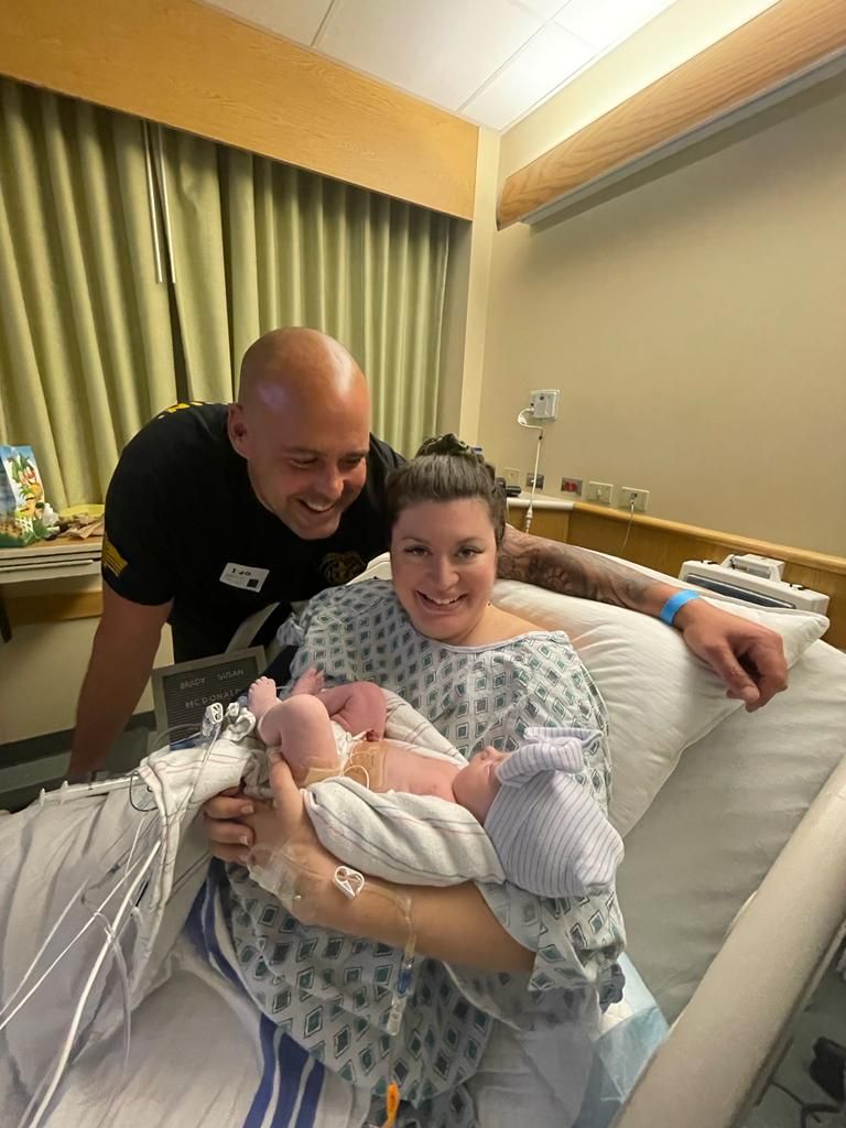 A man and woman are holding a newborn baby in a hospital bed.