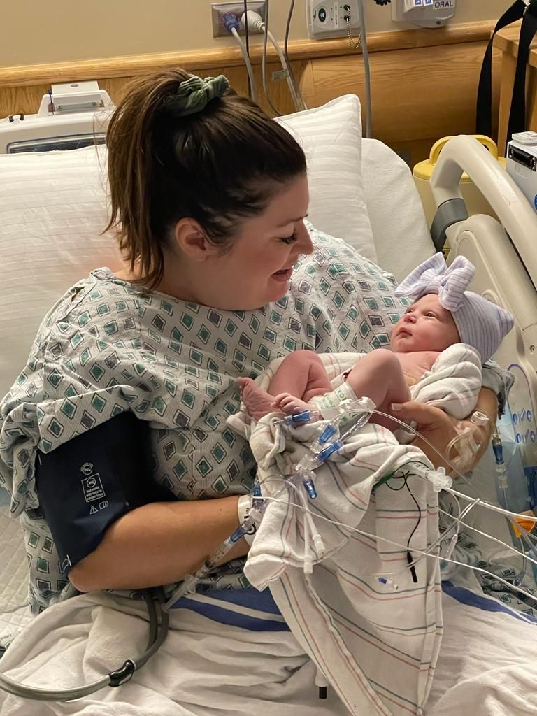 A woman is holding a newborn baby in a hospital bed.