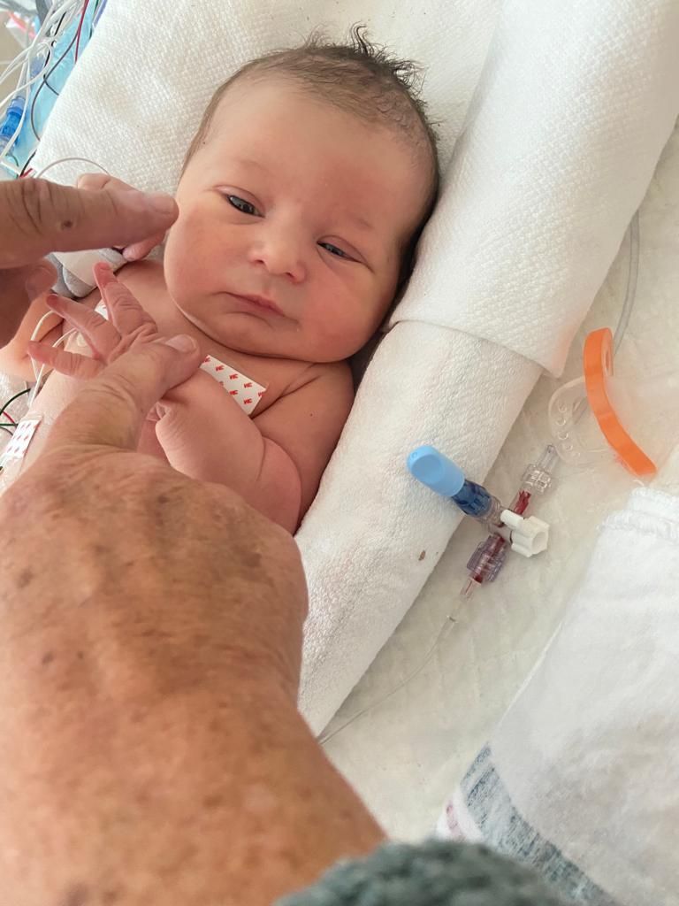 A person is holding a newborn baby in a hospital bed.
