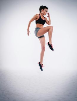 A woman is jumping in the air on a white background.