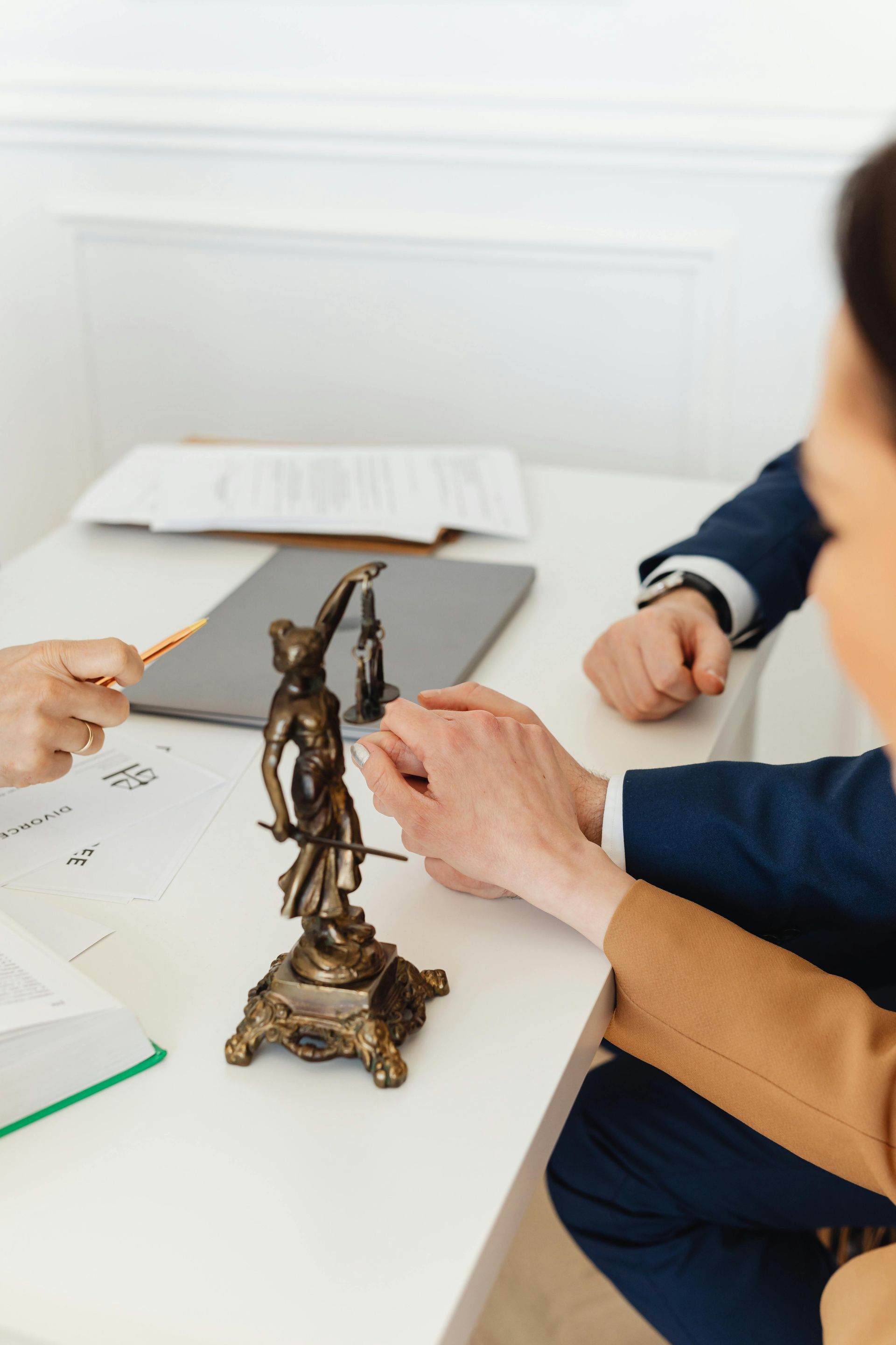 A man and a woman are sitting at a table with a statue of justice on it.