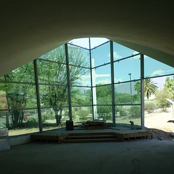 A large room with a lot of windows and trees in the background.