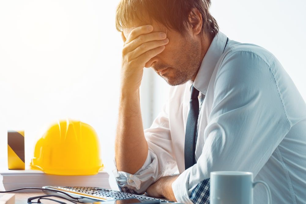 A man is sitting at a desk with his head in his hands.