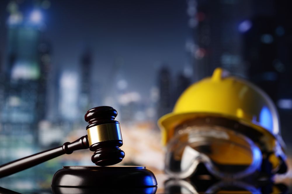 A judge 's gavel is sitting next to a hard hat and safety goggles.