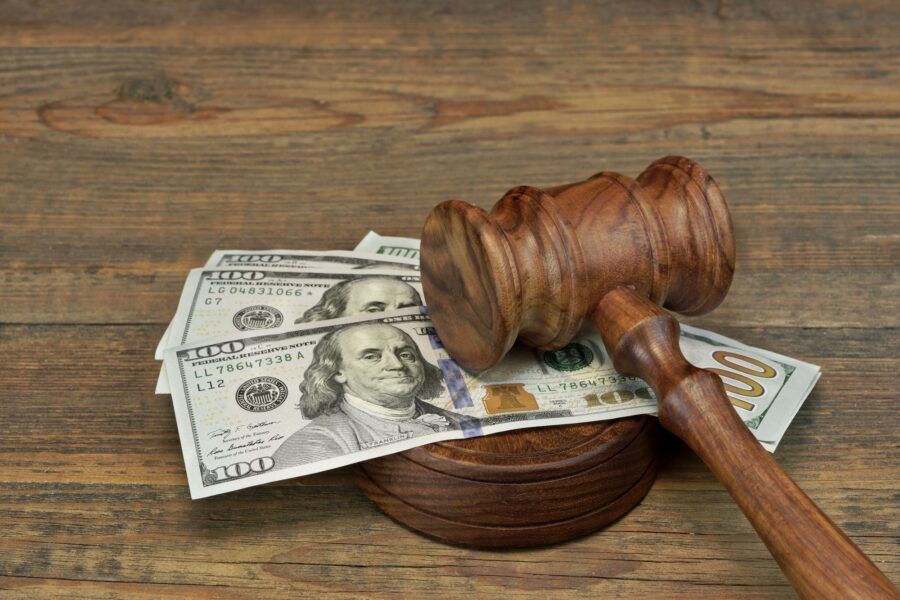 A wooden judge 's gavel sitting on top of a pile of money on a wooden table.