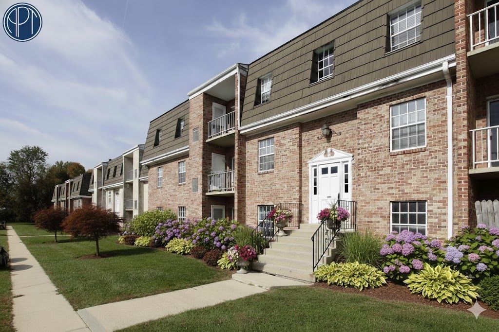 Brick apartment building with green lawn and blue sky.