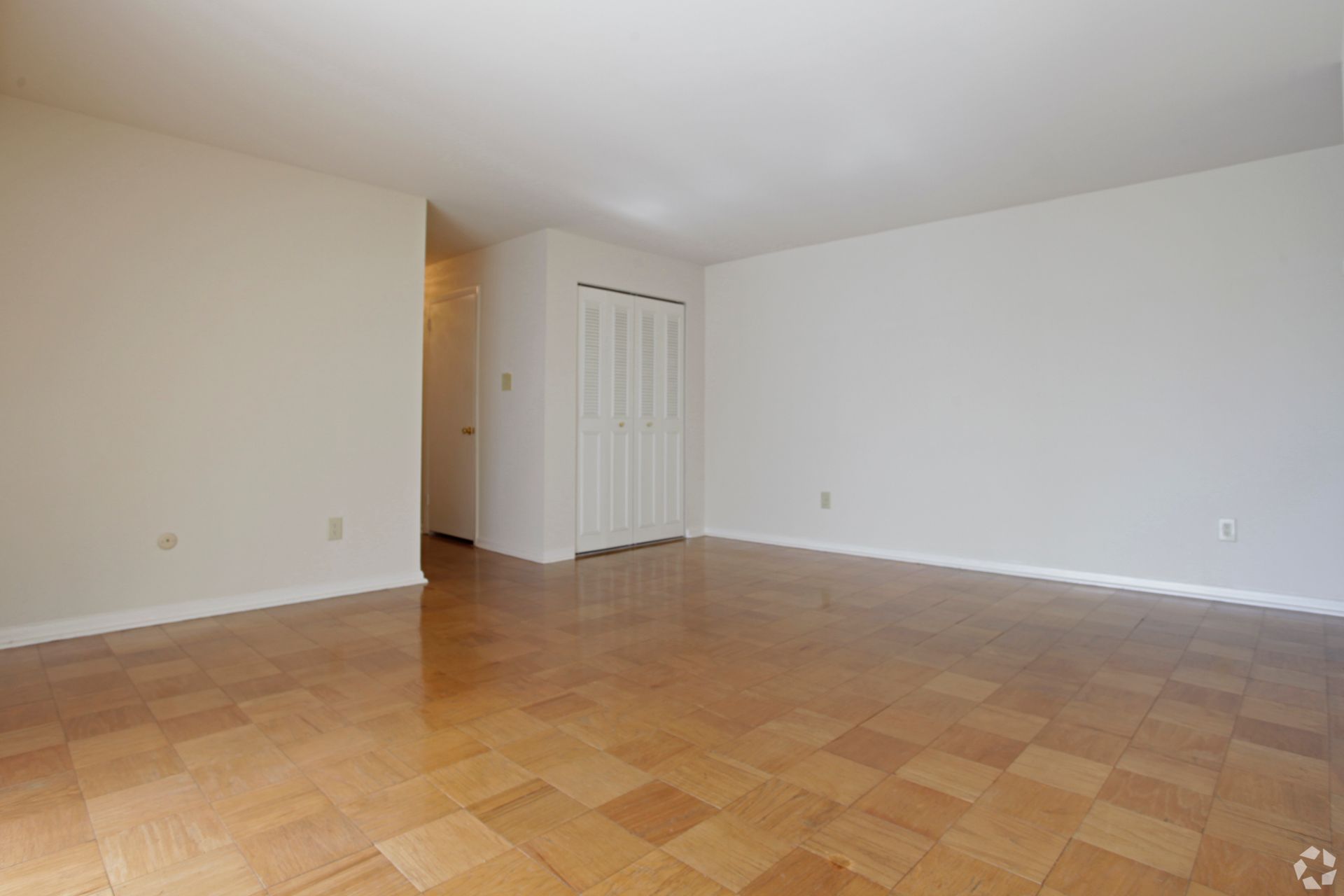 Empty room with hardwood floors, white walls, and a closet.