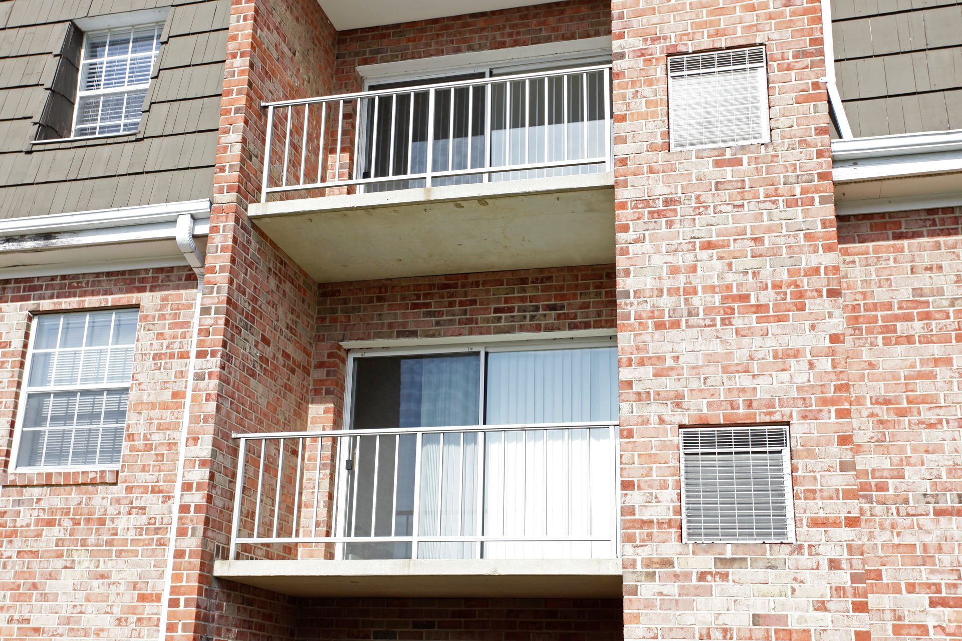 Brick apartment building with balconies and windows.