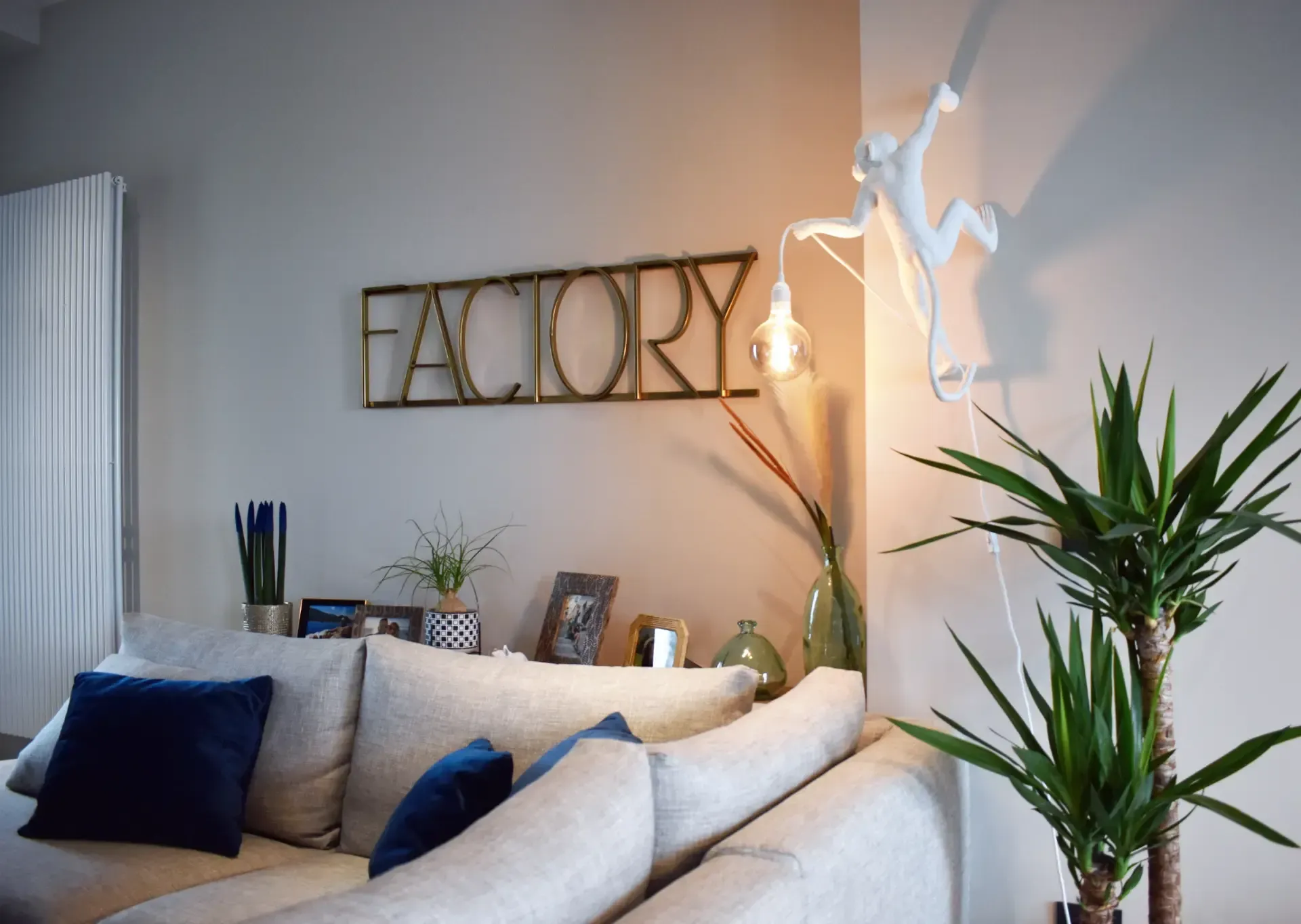 Zona pranzo con tavolo nero, sedie blu, lampade a sospensione grigie e pop art politica sulla parete.