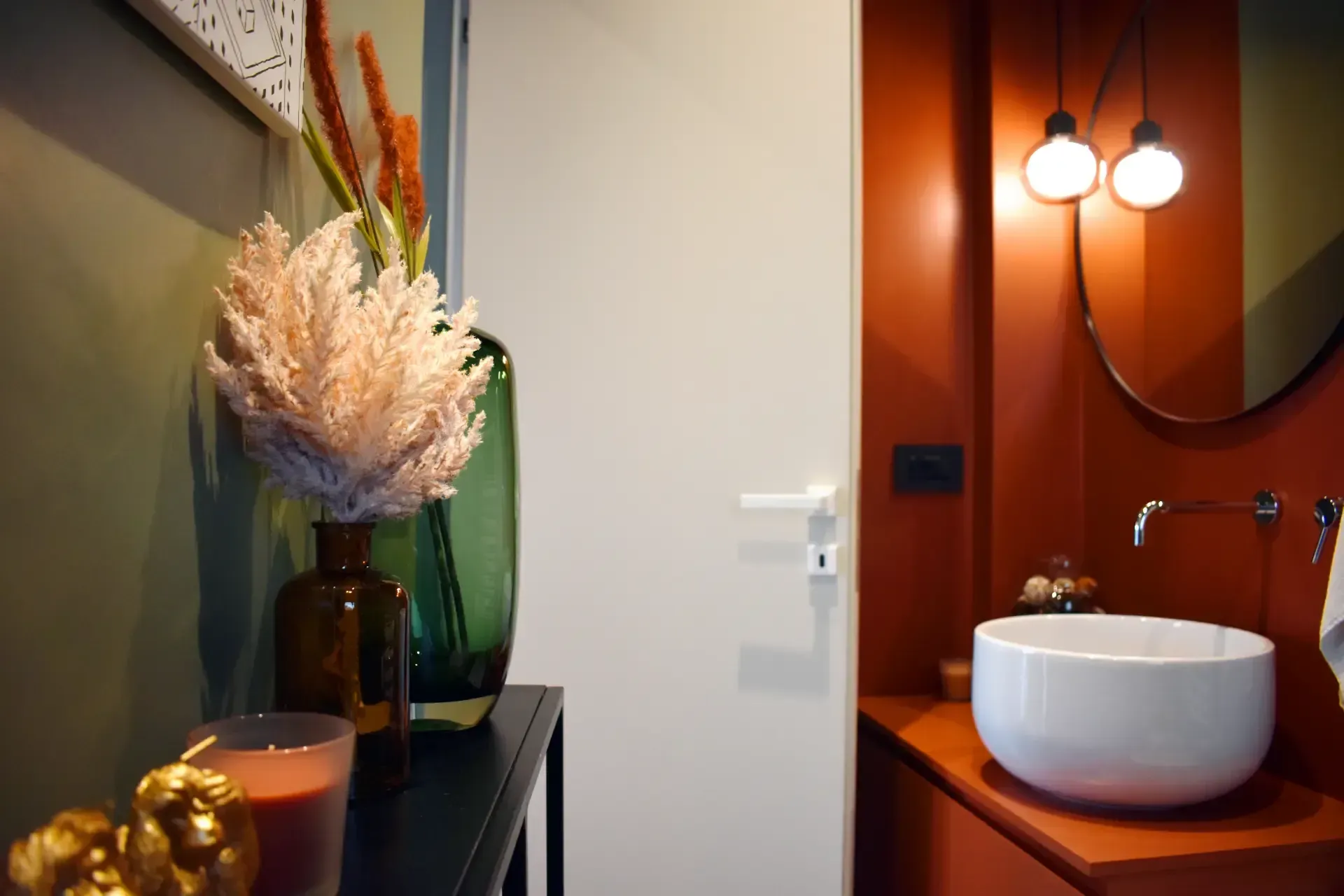 Interno con lavandino bianco, parete arancione e fiori decorativi in ​​vasi.