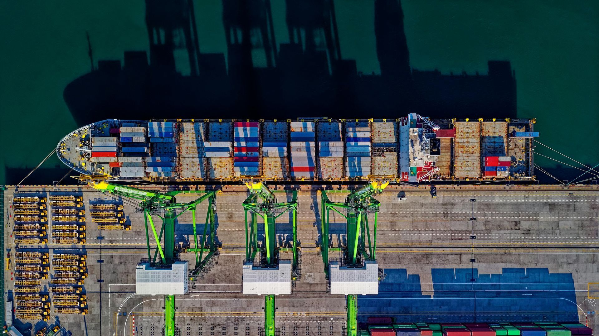An aerial view of a large container ship docked at a port.