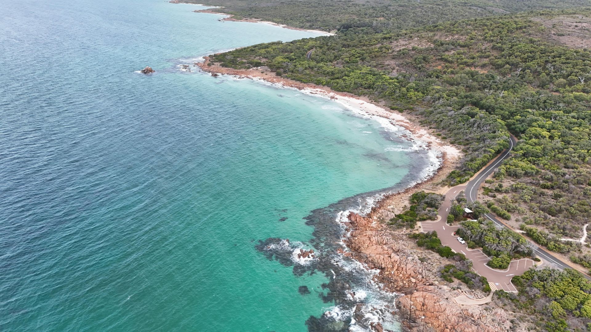 An aerial view of a beach and a body of water surrounded by trees.