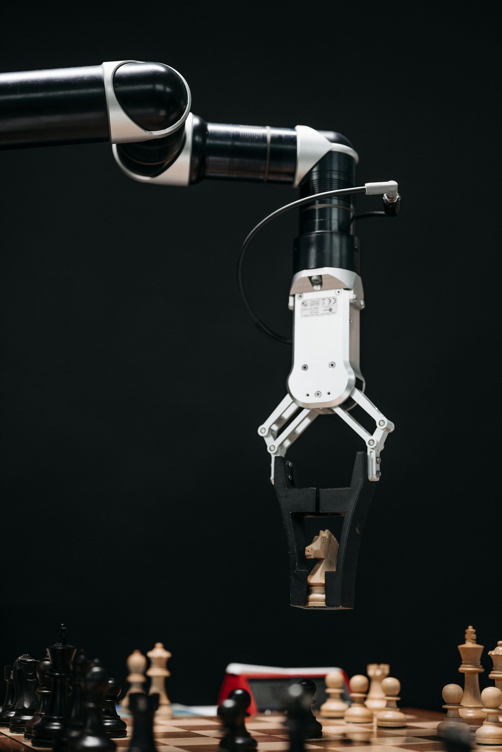A robotic arm is reaching for a chess piece on a chess board.